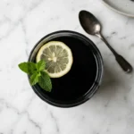 Gelatina negra con carbón activado en vaso oscuro con limón y menta para bajar de peso
